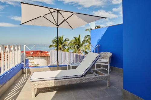 a balcony with a chair and an umbrella at Hotel Luxury Patio Azul in Puerto Vallarta