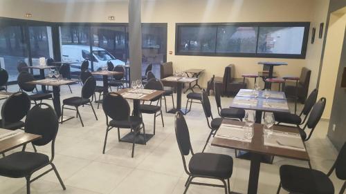 ein Esszimmer mit Tischen, Stühlen und Fenstern in der Unterkunft Hôtel Restaurant Mas del Gall in Castelnou