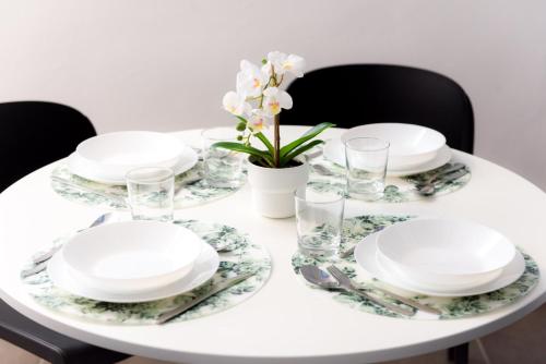 a white table with plates and glasses and flowers at TURINHOMETOWN Residence Apartments in Turin