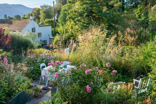 un giardino con tavolo, sedie e fiori di The Mount B&B a Keswick