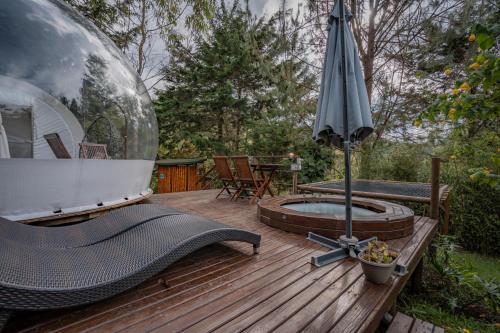 a wooden deck with an umbrella and a hot tub at BubbleSky Glamping 40 min from Medellin in El Retiro