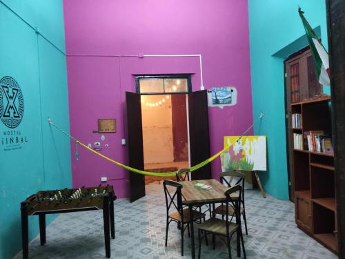 um quarto com uma mesa e cadeiras e uma parede roxa em Hostal Xiinbal em Mérida
