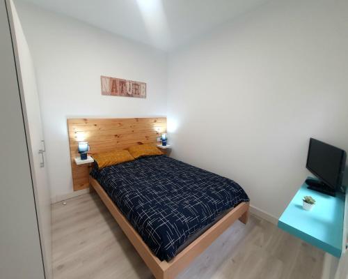 a small bedroom with a bed and a television at Apartamento moderno y acogedor. in Almería