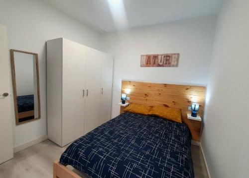 a bedroom with a blue bed and a mirror at Apartamento moderno y acogedor. in Almería