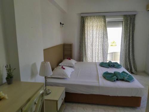 a bedroom with a large bed with a window at Plakia Beach Apartments in Pefki