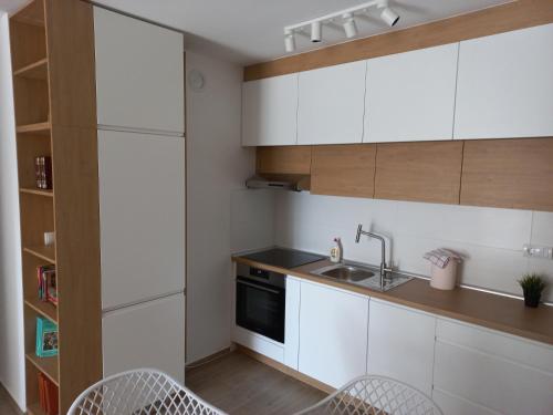 a kitchen with white cabinets and a sink and chairs at Lovely one bedroom apartment in Ub