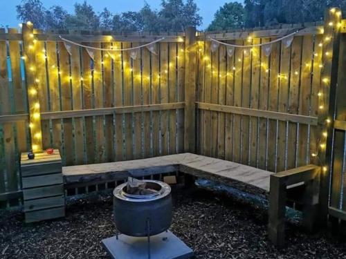 a wooden bench with lights on a fence at Cosy Forest Pod with Wood Fired Hot Tub & Fire Pit in Hambleton