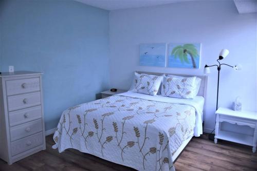 Historic Sebring Downtown Home في سيبرينغ: غرفة نوم بسرير ولحاف ابيض وموقف ليلي