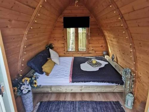 1 dormitorio con 1 cama en una cabaña de madera en Cosy Forest Pod with Wood Fired Hot Tub & Fire Pit, en Hambleton