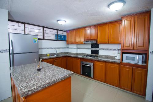 Karey Apartamentos By Danp في سانتا مارتا: مطبخ مع دواليب خشبية وثلاجة حديد قابلة للصدأ