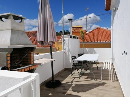 a balcony with an umbrella and a table and chairs at Alojamento Justo - vila de Montargil in Montargil