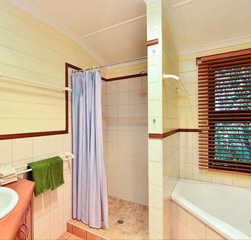 a bathroom with a shower and a tub and a sink at Williams Lodge in Yungaburra