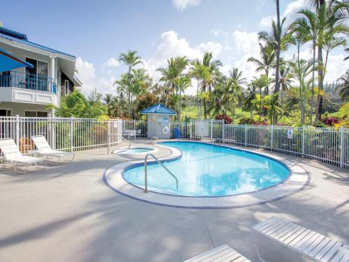 a swimming pool with chairs and a fence at Wyndham Mauna Loa Village in Kailua-Kona