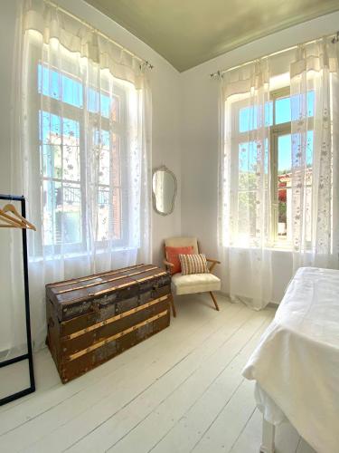 a bedroom with a bed and two windows and a chest at Traditional Stone House in Chandrinos in Khandrinós