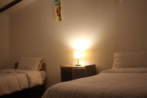 a bedroom with two beds and a lamp on a table at Killari B&B in Ollantaytambo