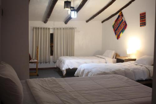 a hotel room with two beds and a window at Killari B&B in Ollantaytambo