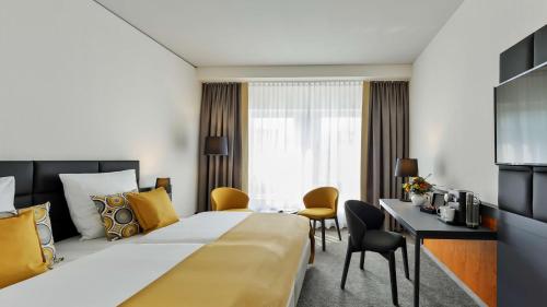 ein Hotelzimmer mit einem großen Bett und einem Schreibtisch in der Unterkunft Dorint Hotel Dresden in Dresden