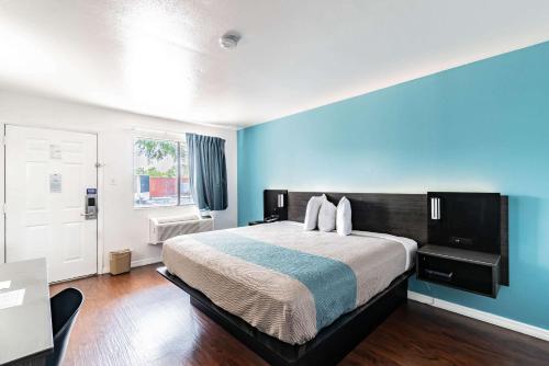 a bedroom with a large bed with blue walls at Motel 6 Tampa Near Fairgrounds - Casino in Tampa