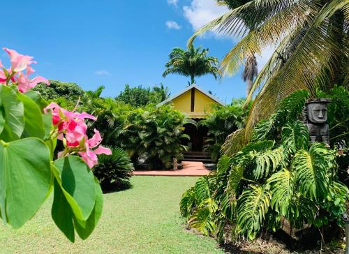 a garden with a yellow house and palm trees at Domaine Saint-François in Saint-François