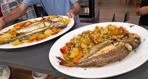due piatti di pesce e verdure su un tavolo di IL MIO a Ksamil