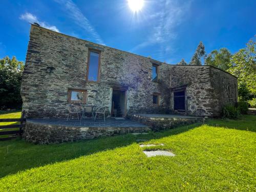 uma casa de pedra com um pátio na relva em Galicia Retreat em Santa Marta de Ortigueira