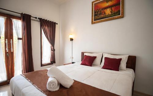 a bedroom with a large white bed with red pillows at Santhi Guna Bungalow in Nusa Penida