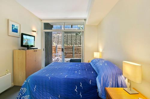 a bedroom with a blue bed and a window at Apartment 20 Kalimna in Lorne