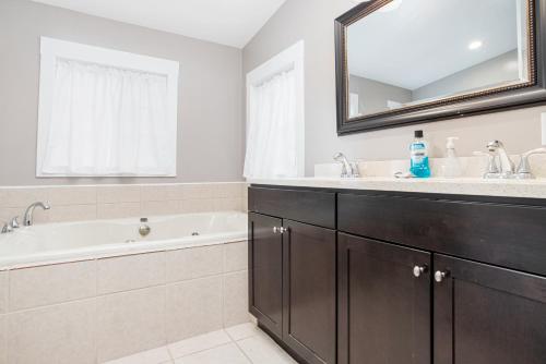 een badkamer met een wastafel, een bad en een spiegel bij Serenity Acres in New Buffalo