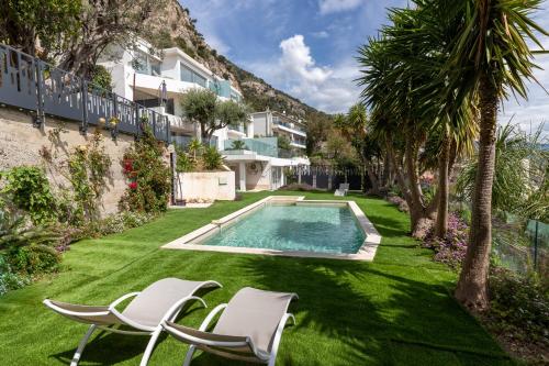 Saint-Antoine的住宿－Mont des Olives - Cap D'ail- app1，一个带两把椅子的庭院和一个游泳池