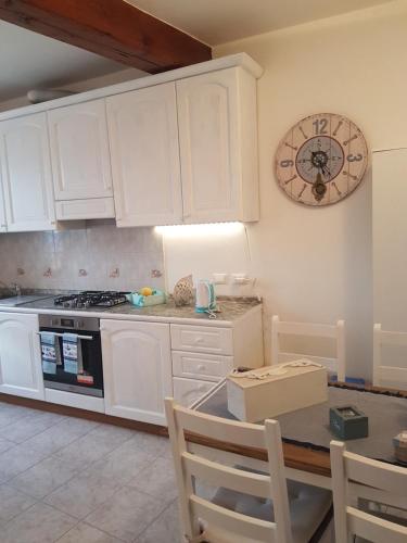 a kitchen with white cabinets and a clock on the wall at Casa Mafalda in Corniglia