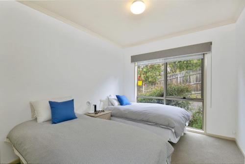 two beds in a room with a window at Lorne Central in Lorne