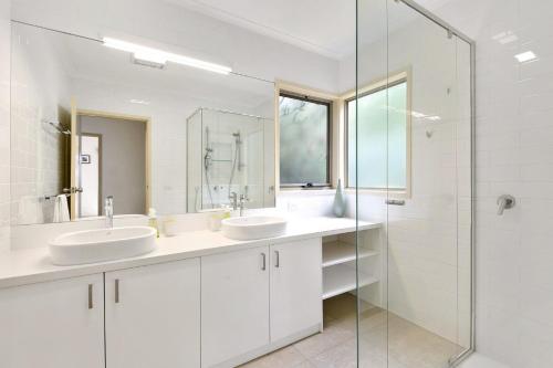 a white bathroom with two sinks and a shower at Lorne Central in Lorne