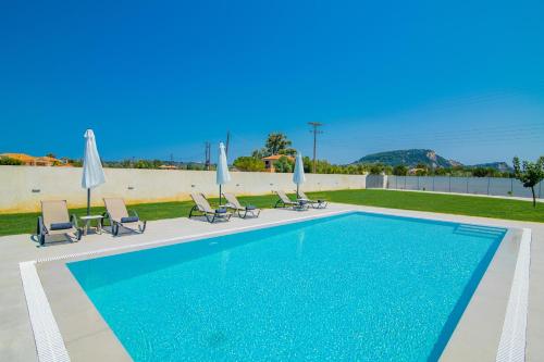 a swimming pool with chairs and umbrellas at Nimar Villa in Gaïtánion