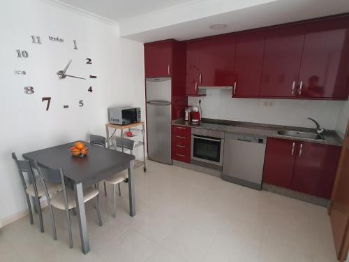 a kitchen with red cabinets and a table with chairs at Alborada in Viveiro