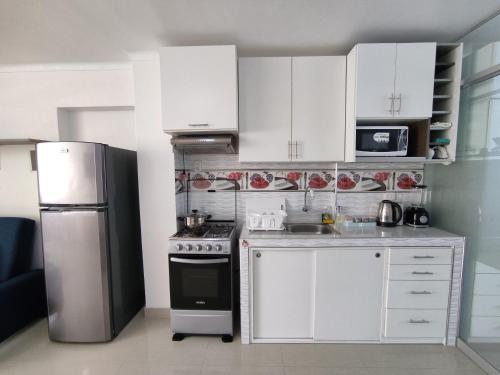 a kitchen with white cabinets and a stainless steel refrigerator at MINI DEPARTAMENTO LAS VEGAS in Chimbote