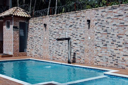 a swimming pool with a water fountain next to a brick wall at Solar Maresias Flats in Maresias