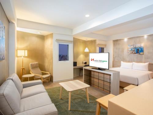 a hotel room with a bed and a flat screen tv at Swiss-Belexpress Cilegon in Cilegon