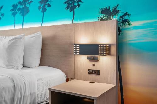 a hotel room with a bed and a nightstand next to a table at Avania Inn of Santa Barbara in Santa Barbara