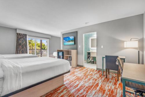 a hotel room with a bed and a desk and a table at Avania Inn of Santa Barbara in Santa Barbara