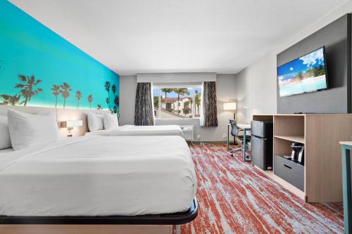 a hotel room with a large bed and a flat screen tv at Avania Inn of Santa Barbara in Santa Barbara