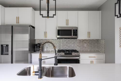 a kitchen with white cabinets and a stainless steel sink at SAND HILL COTTAGE 3 Bedroom Home near PURDUE! River & Park View in West Lafayette