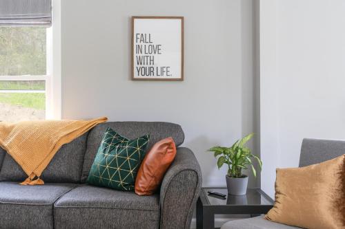 a living room with a gray couch and a table at SAND HILL COTTAGE 3 Bedroom Home near PURDUE! River & Park View in West Lafayette