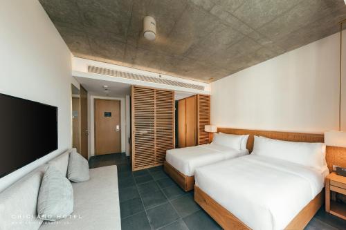 a hotel room with two beds and a flat screen tv at Chicland Boutique Danang Beach Hotel in Da Nang