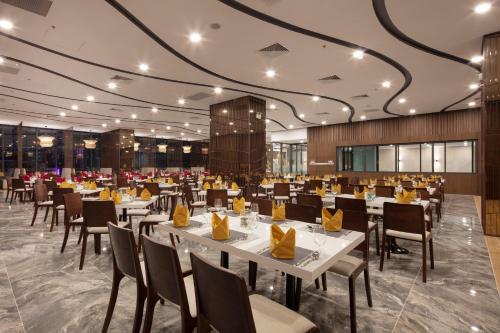 a restaurant with white tables and chairs and yellow napkins at DQua Hotel in Nha Trang