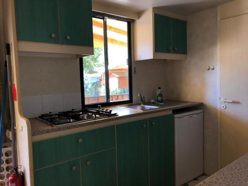 cocina con armarios verdes, fregadero y ventana en Toskana, Viareggio,Chalet 27 mit Klimaanlage und Wlan en Viareggio