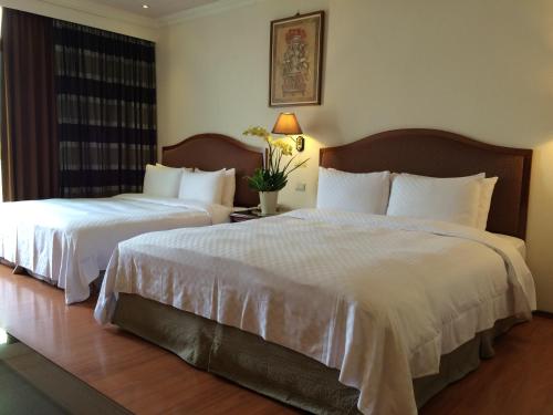 two beds in a hotel room with white sheets at Chia Shih Pao Hotel in Taibao