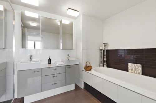 Baño blanco con 2 lavabos y bañera en Lorne Chalet Apartment 42, en Lorne