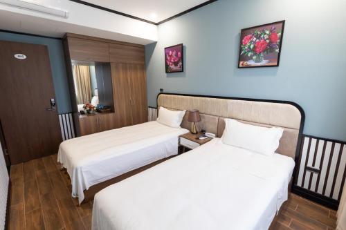 duas camas num quarto de hotel com lençóis brancos em Hanz Boutique Hotel em Ha Long