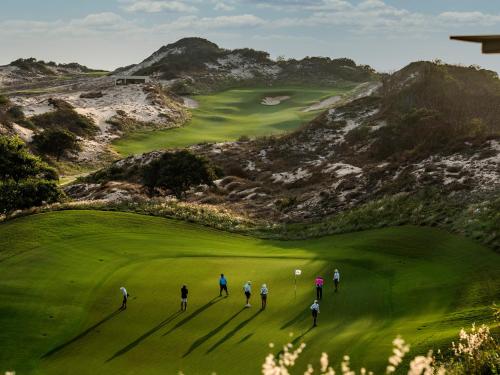 a group of people walking on a golf course at Holiday Inn Resort Ho Tram Beach by IHG in Ho Tram