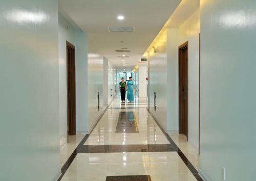 two people walking down a hallway in a building at Khách Sạn Hoa Ban Trắng in Sơn La